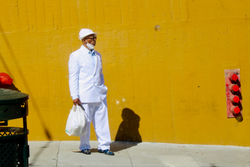 meredith pritchard man dressed in all white in front of a yellow wall